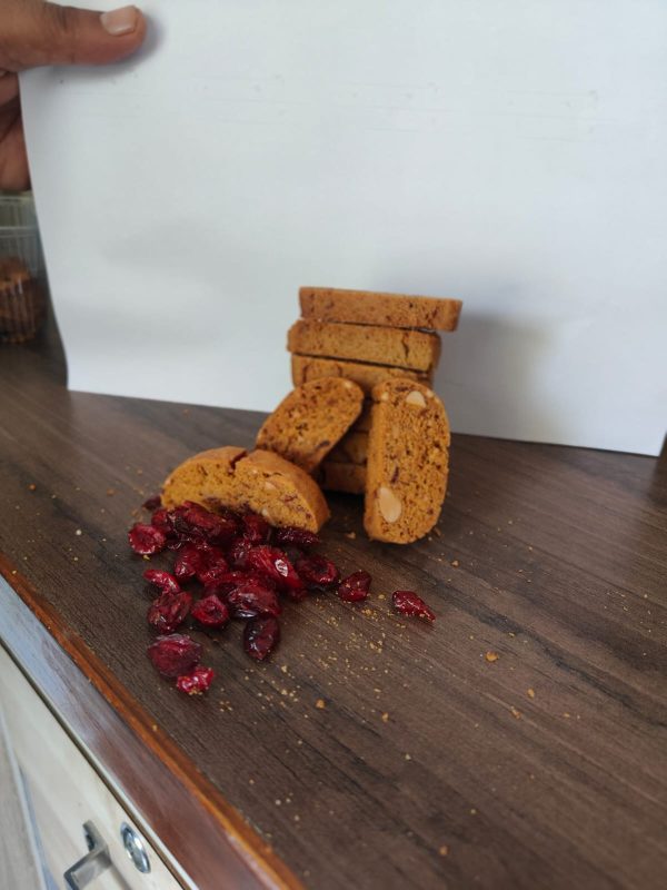 A-close-up-of-cranberry-biscotti-cookies-with-a-few-cranberries-on-a-rustic-table-surface