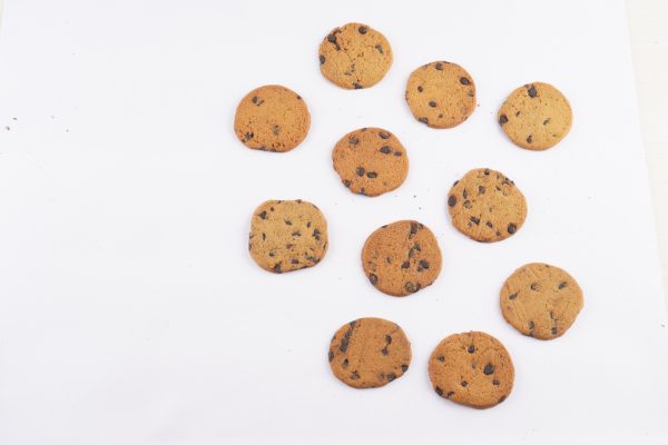 A-group-of-Besan-Chocochip-cookies-arranged-on-a-white-surface-showcasing-their-chocolate-chips-and-golden-brown-color.
