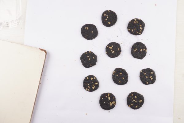 A-white-paper-displaying-several-dark-chocolate-oat-cookies-arranged-neatly-on-top