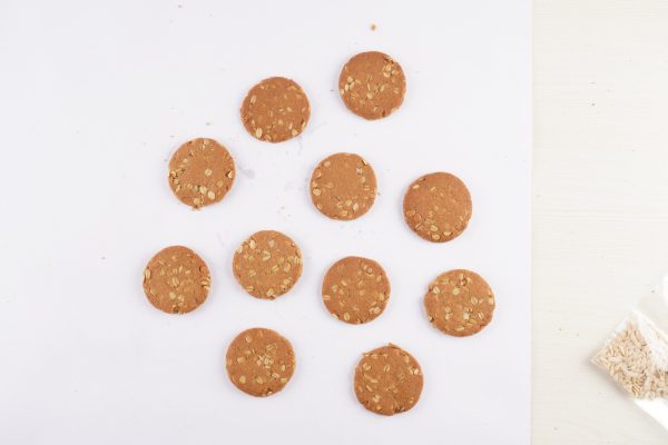 A-white-table-displays-a-bowl-of-cookies-alongside-a-bag-of-honey-oats